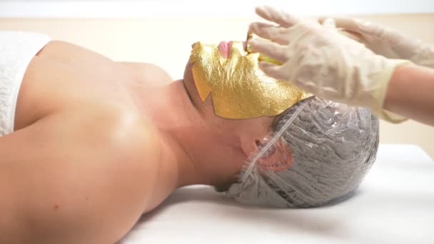 Thérapie spa pour les beaux hommes recevant un masque facial. 4k. Au ralenti. Accueil d'un cosmétologue. masque doré — Video