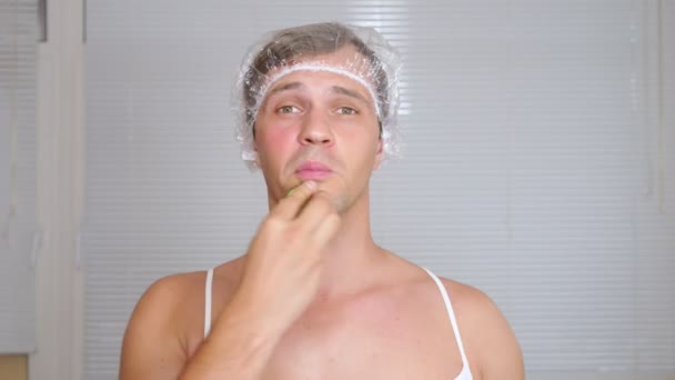 Vreemde man met gezicht pack. Een jonge man doet cosmetische ingrepen voor het gezicht van een huis voor een spiegel. 4k — Stockvideo