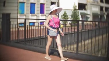 bir genç şık turist kadın, şehrin sokaklarında elini kolunu sallaya dönüyor. sıcak yaz gününde. 4 k, ağır çekim, yakın çekim.