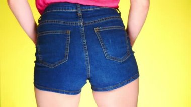 Kısa kot mavi şortlu kız. Arkadan yakından görmek. Yaz taze tarzı. 4k, ağır çekim