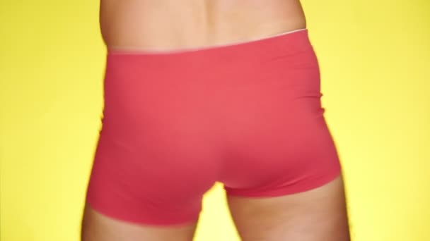 Um homem de boxers vermelhos a dançar num fundo amarelo. close-up. 4k, câmera lenta — Vídeo de Stock