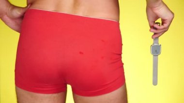 sarı bir arka plan üzerinde kırmızı boksörler adam. adam bir kol saati tutuyor. 4k, ağır çekim