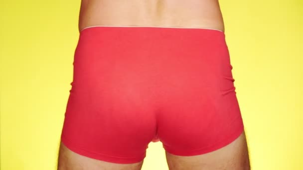 Um homem de boxers vermelhos a dançar num fundo amarelo. close-up. 4k, câmera lenta — Vídeo de Stock