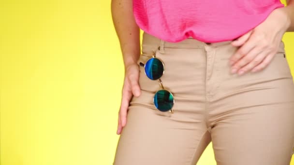 Девушка в стильных узких бежевых джинсах и модных аксессуарах, круглых зеркальных солнцезащитных очках. Летний свежий стиль. крупный план, 4k, замедленная съемка — стоковое видео