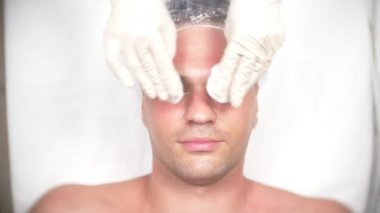 Yakışıklı erkekler yüz maskesi alma için spa terapisi. 4 k. ağır çekim. Bir güzellik uzmanı alımı