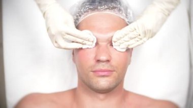 Yakışıklı erkekler yüz maskesi alma için spa terapisi. 4 k. ağır çekim. Bir güzellik uzmanı alımı