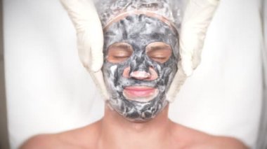 Yakışıklı erkekler yüz maskesi alma için spa terapisi. 4 k. ağır çekim. Bir güzellik uzmanı alımı