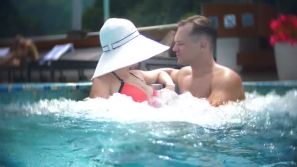 슬로우 모션, 가까이, 초상화입니다. 행복 한 부부 사랑 하는 남자 고 여자 일광욕 하 고 화창한 날에 산 풍경 배경 고급 스러운 수영장에서 휴식. 산악 리조트 야외 수영장입니다. 4 k — 비디오