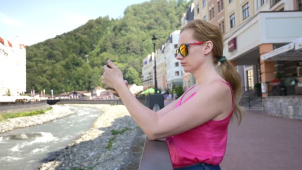 Sıcak güneşli bir günde şehirde yürüyüş smartphone kullanan kadın. Seyahat. Bir yaşam biçimi kavramı. Gadget'ı modern iletişim teknolojisi. 4k, ağır çekim — Stok video