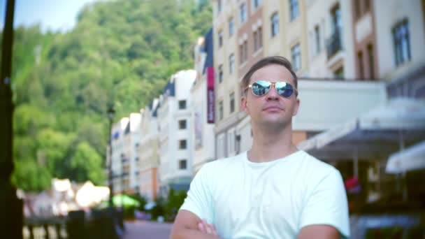 Jeune homme élégant, posant dans les rues de la ville. par une chaude journée d'été. il regarde la caméra et sourit. 4k, ralenti, gros plan . — Video