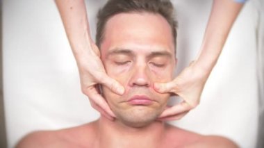Adam bir yüz almak masaj. Yüz ve boyun masaj. kasmetologist ofiste yalan. 4k, yavaş hareket, görünümü top