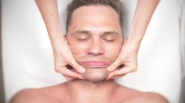 Adam bir yüz almak masaj. Yüz ve boyun masaj. kasmetologist ofiste yalan. 4k, yavaş hareket, görünümü top