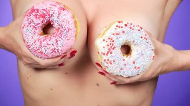 yakın çekim, çörek ve erkek göğüsler. 4k, ağır çekim. çörek porno. Çörek sever. Fast Food ve seksi bir kadın. Moda minimal sanat