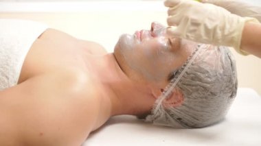 Yakışıklı erkekler yüz maskesi alma için spa terapisi. 4 k. ağır çekim. Bir güzellik uzmanı alımı