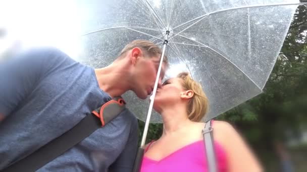 Um casal amoroso de homens e mulheres está passeando sob um guarda-chuva no parque em um dia chuvoso de verão. 4K. câmera de ação — Vídeo de Stock