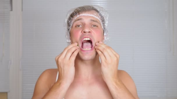 Étrange homme avec un sac visage. Un jeune homme fait des interventions cosmétiques pour le visage d'une maison devant un miroir. 4k — Video