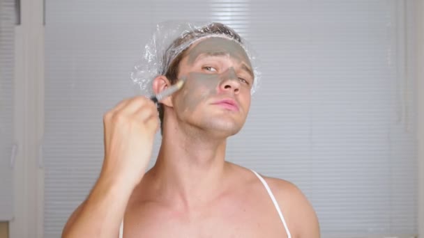 Étrange homme avec un sac visage. Un jeune homme fait des interventions cosmétiques pour le visage d'une maison devant un miroir. 4k — Video