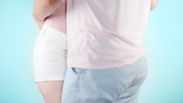 Close up. the hips. fashion image of a young sexy couple, hugs at a light blue background, 4k, slow-motion — Stock Video