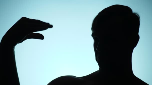 Silhouette eines Mannes auf blauem Hintergrund. der lustige Mann spielt das Schattentheater. 4k, Zeitlupe — Stockvideo