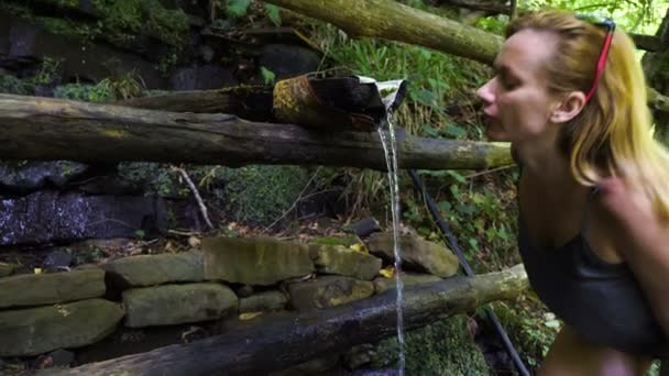 La mujer se curva para saciar su sed. Agua potable de la montaña. fuente limpia. 4k, cámara lenta — Vídeos de Stock