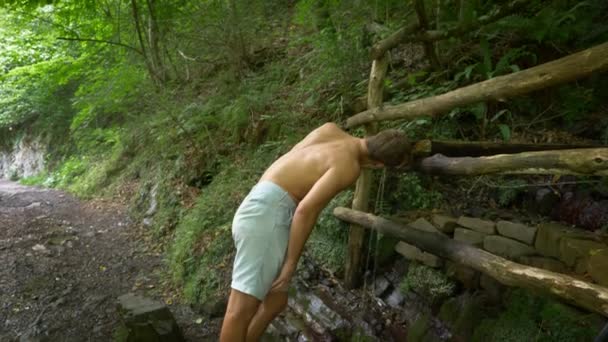 O homem curva-se para saciar a sede. A beber água da montanha. fonte limpa. 4k, câmera lenta — Vídeo de Stock