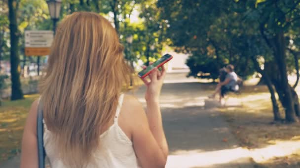 heureuse jeune femme parlant au téléphone, marchant le long du front de mer par une chaude journée ensoleillée d'été. 4k, au ralenti 