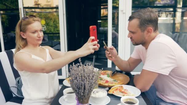 Pareja en un café al aire libre. Hombre y mujer en una cita. un socio mira su teléfono, el segundo trata de hablar con él. 4k, cámara lenta . — Vídeos de Stock