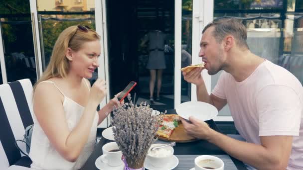 Pareja en un café al aire libre. Hombre y mujer en una cita. un socio mira su teléfono, el segundo trata de hablar con él. 4k, cámara lenta . — Vídeos de Stock