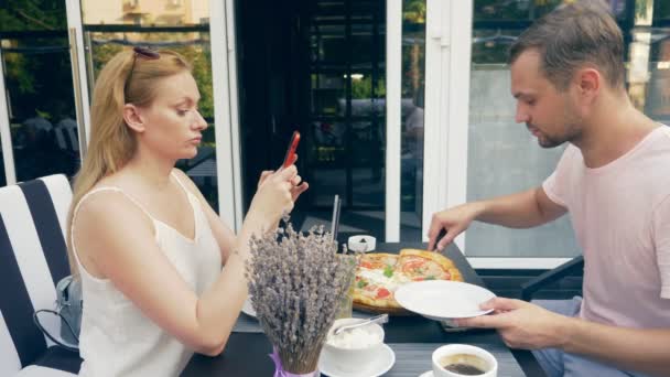 Couple dans un café extérieur. Homme et femme en rendez-vous. un partenaire regarde son téléphone, le second essaie de lui parler. 4k, au ralenti . — Video