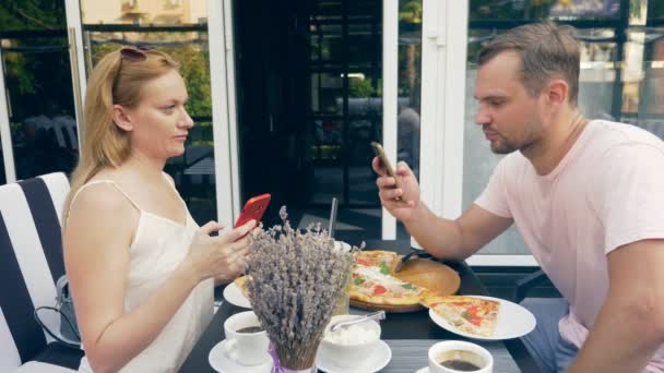 Pareja en un café al aire libre. Hombre y mujer en una cita. un socio mira su teléfono, el segundo trata de hablar con él. 4k, cámara lenta . — Vídeos de Stock