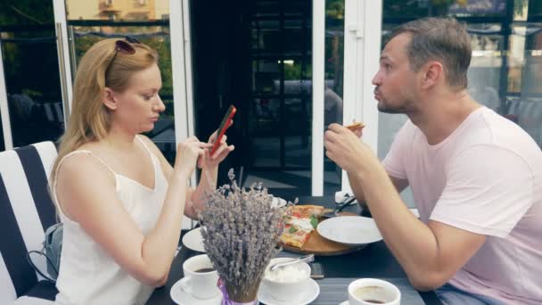 Paar in einem Café im Freien. Mann und Frau bei einem Date. Ein Partner schaut auf sein Handy, der zweite versucht, mit ihm zu sprechen. 4k, Zeitlupe. — Stockvideo