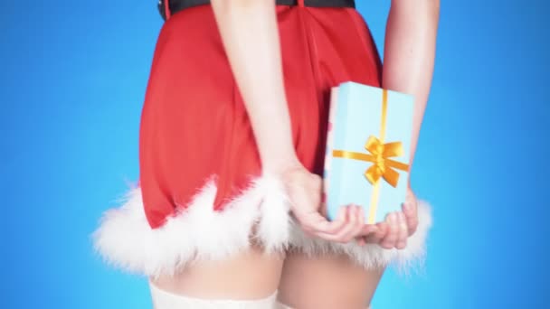 Vacaciones de Navidad. joven mujer atractiva en un disfraz de doncella de nieve con un regalo, bailando sobre un fondo azul. primer plano, cámara lenta, 4k — Vídeo de stock