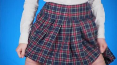 Genç kız, bir etek altında gizli kalça üzerinde yazılı levha hile midsection. 4 k, yakın çekim, mavi arka plan, ağır çekim çekim.