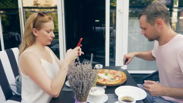 Pár ve venkovní kavárně. Muž a žena na datum. jeden partner se dívá na jeho telefon, druhý snaží s ním mluvit. 4k, pomalý pohyb. — Stock video