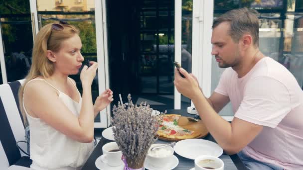 屋外カフェのカップル。男と女の日に。1 つのパートナーは、彼の携帯電話は、彼と話をする 2 番目の試行で見えます。4 k、スローモーション. — ストック動画