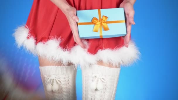 Vacanze di Natale. giovane donna attraente in costume da nubile di neve con un regalo, ballare su uno sfondo blu. primo piano, rallentatore, 4k — Video Stock