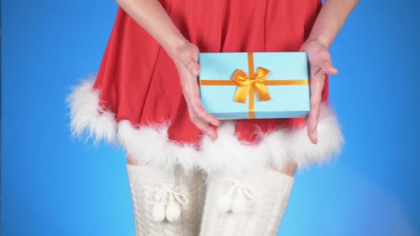 Рождественские каникулы. молодая привлекательная женщина в костюме снегурочки с подарком, танцующая на синем фоне. макро, замедленная съемка, 4k — стоковое видео
