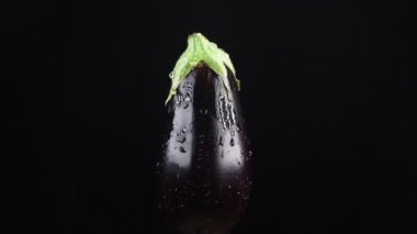 Patlıcan, - kadar yakın. Siyah bir arka plan üzerinde dönen bir elma üzerinde su damlacıkları kalmaktadır. süper ağır çekim.