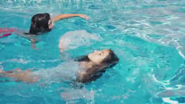 Два счастливых подростка, брат и сестра, плавают в гонке в бассейне. Медленное движение. Стадикам выстрелил. 4k — стоковое видео