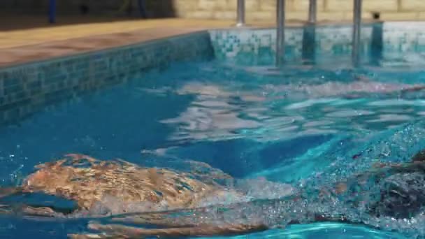 Two happy teenagers, a brother and sister, are swimming in a race in the pool. Slow motion. steadicam shot. 4k — Stock Video