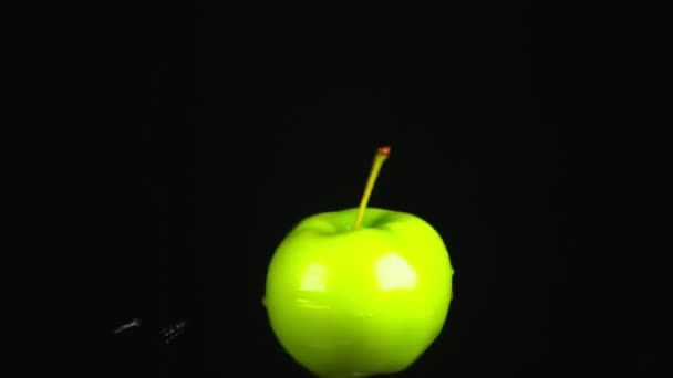 Pomme verte, tout près. Des gouttes d'eau tombent sur une pomme tournante sur un fond noir. super ralenti . — Video