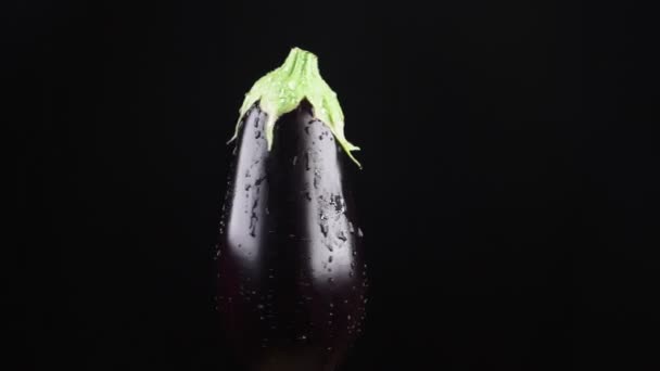 Berenjena, de cerca. Gotas de agua caen sobre una manzana giratoria sobre un fondo negro. super cámara lenta . — Vídeos de Stock