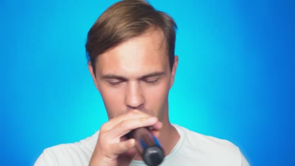 En galet rolig ung man sjunger sånger i en mikrofon. färg bakgrunden, närbild. 4k, Slowmotion — Stockvideo
