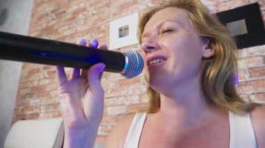 Yakın çekim. bir kadın çığlığı için bir mikrofon. bir kadın bir ev ortamında bir mikrofona karaoke şarkı söylüyor. 4k, ağır çekim