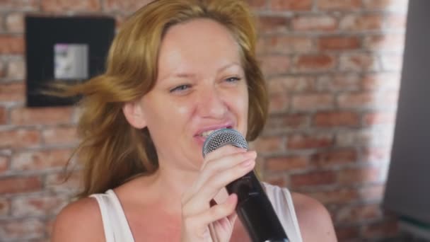 Close-up. een vrouw schreeuwen om een microfoon. een vrouw zingt karaoke in een microfoon in een huis het plaatsen. 4k, slow-motion — Stockvideo