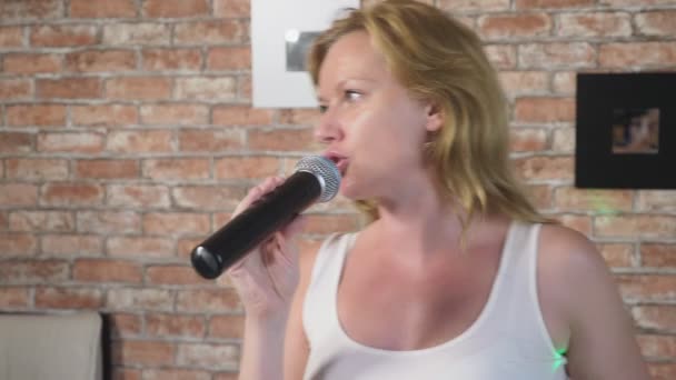 Fecha. uma mulher a gritar para um microfone. uma mulher canta karaoke em um microfone em um ambiente doméstico. 4k, câmera lenta — Vídeo de Stock