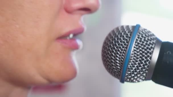Z bliska. kobieta krzyczy do mikrofonu. Kobieta śpiewa karaoke do mikrofonu w warunkach domowych. 4k, zwolnionym tempie — Wideo stockowe