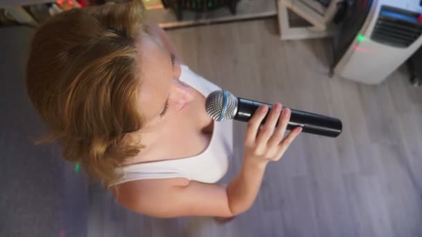 De cerca. una mujer gritando a un micrófono. una mujer canta karaoke en un micrófono en un entorno familiar. 4k, cámara lenta — Vídeos de Stock