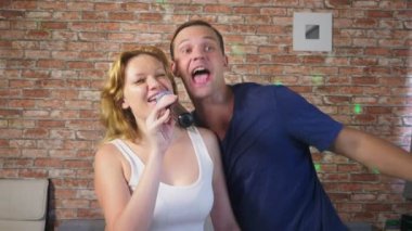 Kaç şarkı şarkı - karaoke takım. iki adam ve kadın kanepede oturan bir mikrofona şarkıları söyleyerek. 4k, ağır çekim