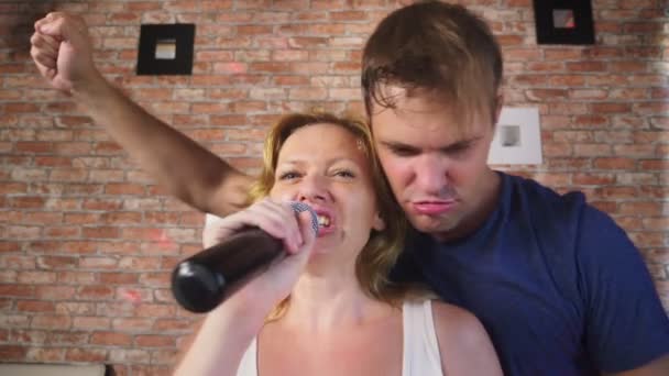 Paar zingen lied - karaoke team. paar man en vrouw zingen liederen in een microfoon die zittend op de Bank. 4k, slow-motion — Stockvideo